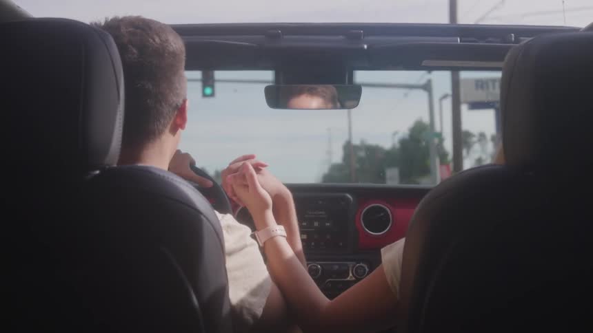 Couple holding hands while driving in a convertible
