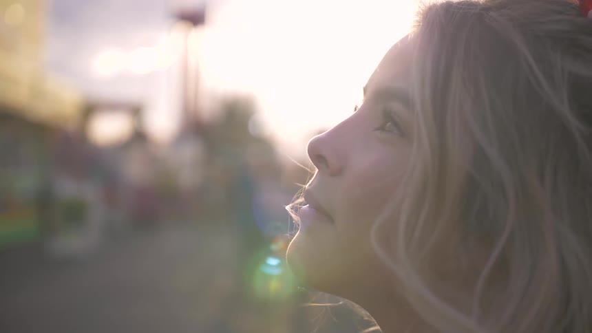 A young woman is standing outside and looks up at the sky