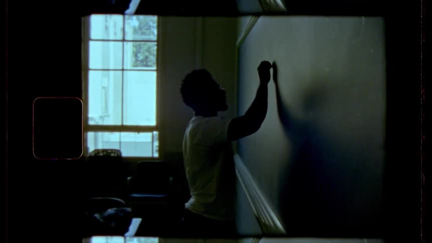 A man is writing on a chalk board indoors