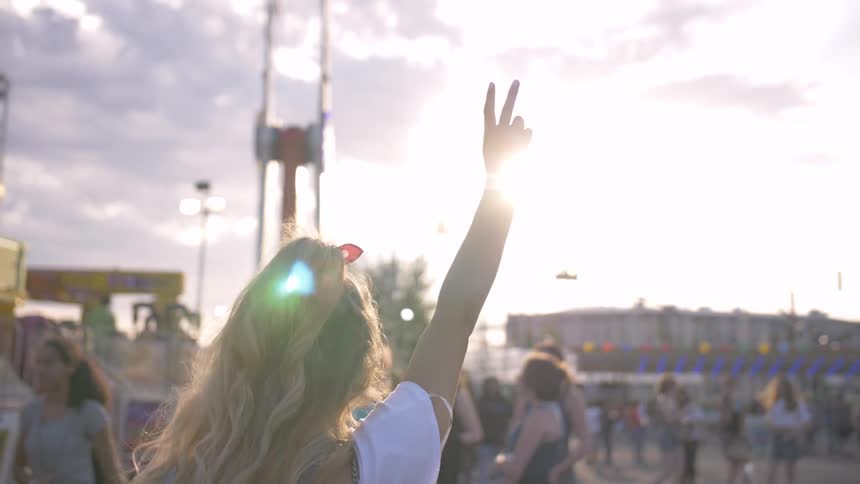 A female raises the peace sign while standing at a carnival