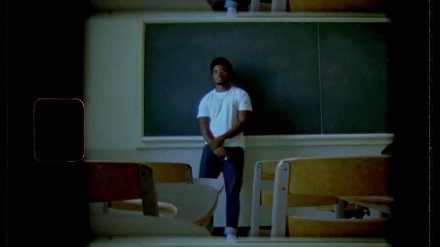 Male student leaning against a chalk board in a classroom
