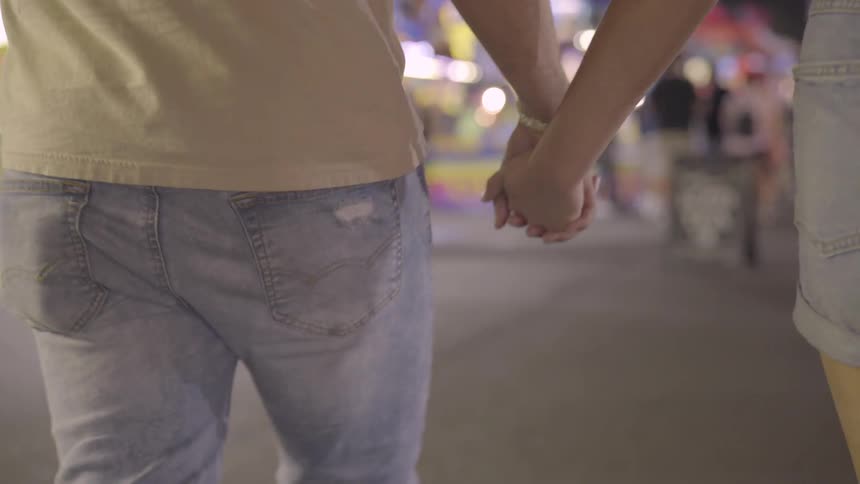 A girl and boy walk along holding hands