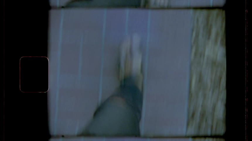 Film footage of a person walking on a sidewalk