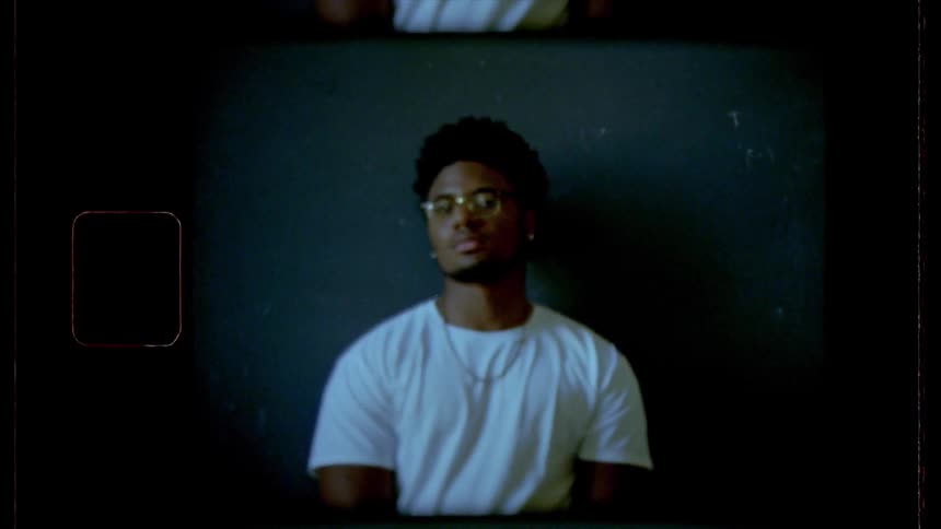 Black male posing against a black wall for a picture