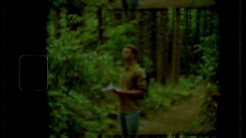 A man taking notes while standing on a forest path