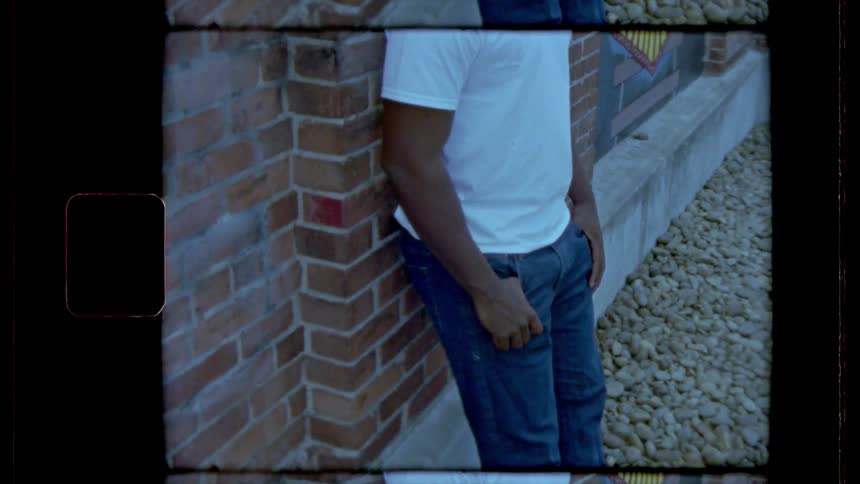 Film footage of a person leaning against a brick wall