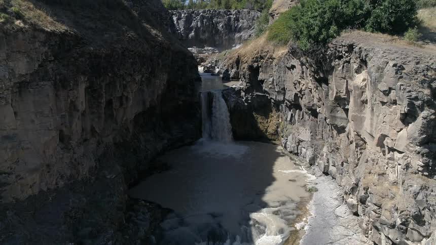 A waterfall flows in to muddy waters below