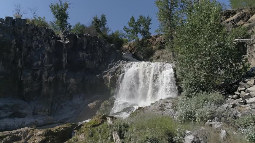 A water fall crashes over the rocks in to the river below