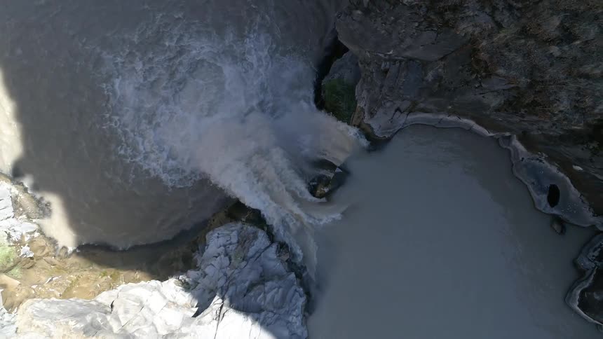 A river flows rapidly into a powerful waterfall that pours tons of water down below it