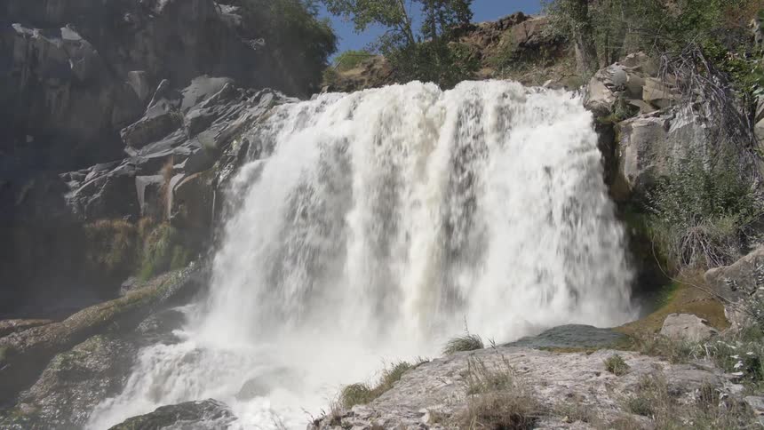 A mist rises from a water cascading down a cliff