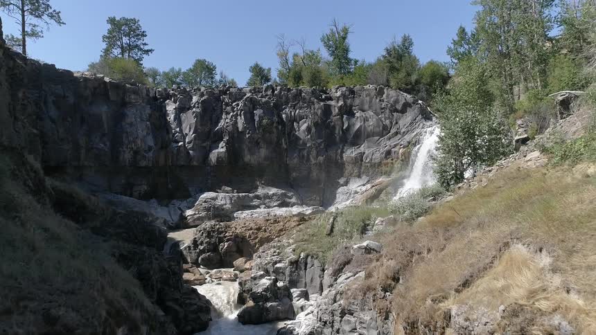 A small waterfall flows into a river surrounded by rocks