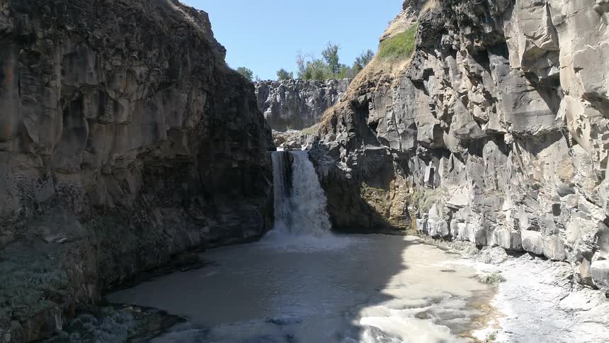 A waterfall flows into a muddy ravine