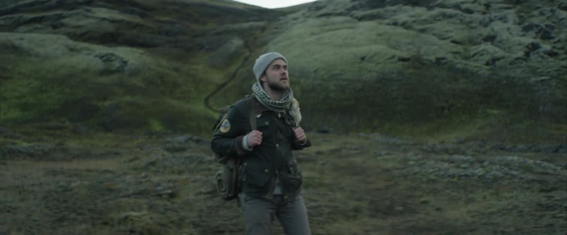 A hiker looking around at the hills around him