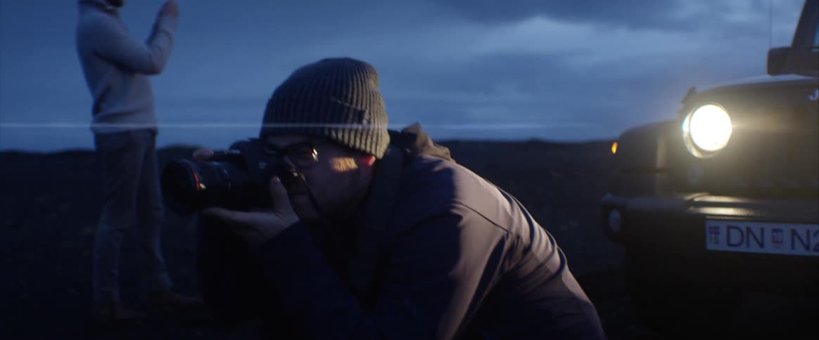 Two men take pictures outside at night