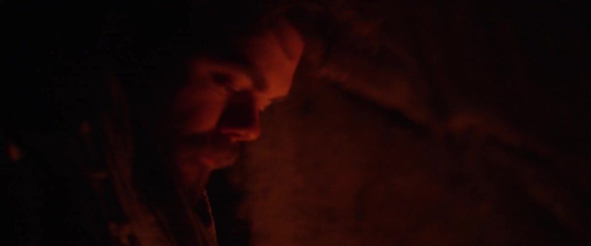 A man sits beside a fire outside
