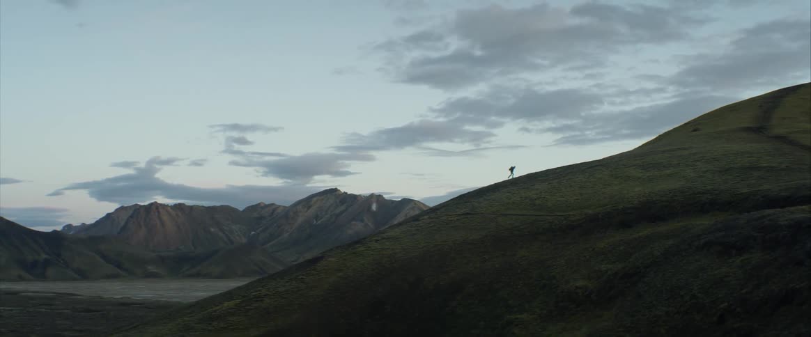 A person walking up a grassy hill outdoors