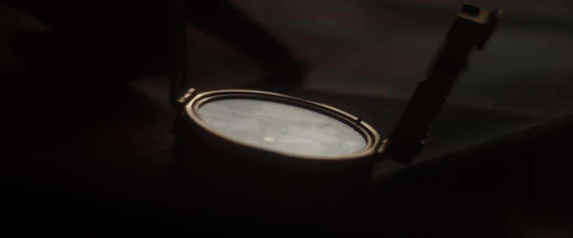 An open compass sits on a table where a finger is tracing a route on a map