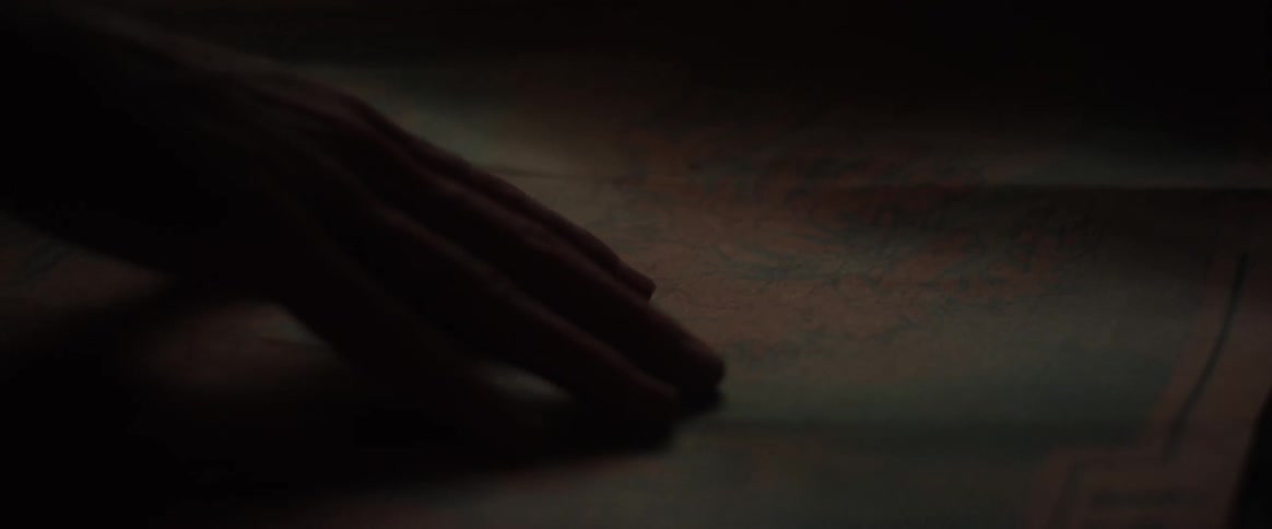 A person running their hand over a map in a dark room