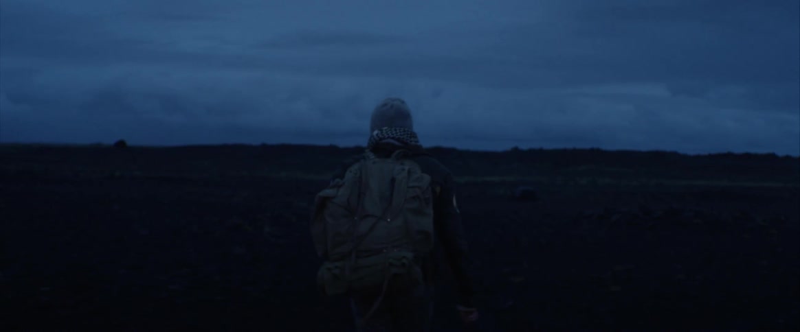 A person hiking along a large open grass plain at night
