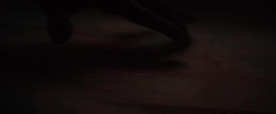 Fingers skim over a wooden surface in a dark room