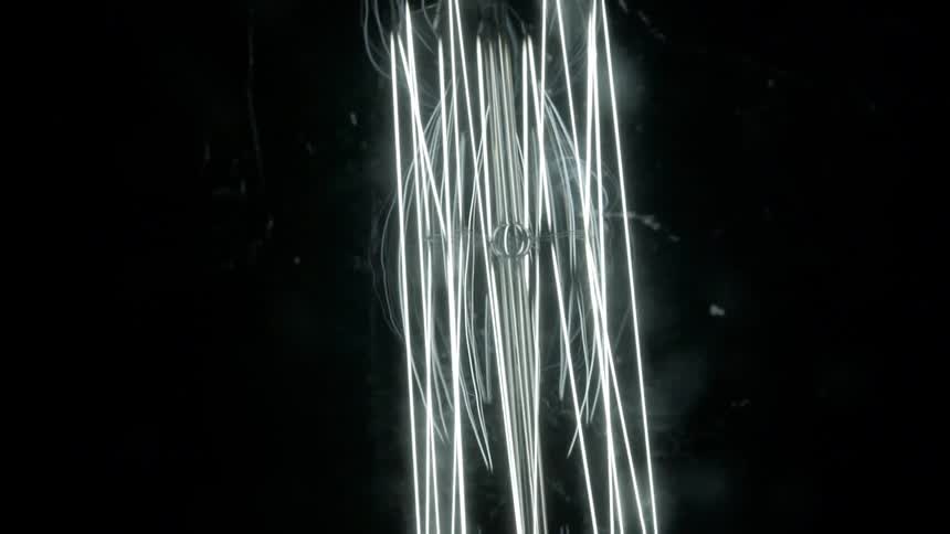 An array of surreal wire thin lights hangs in a darkened room