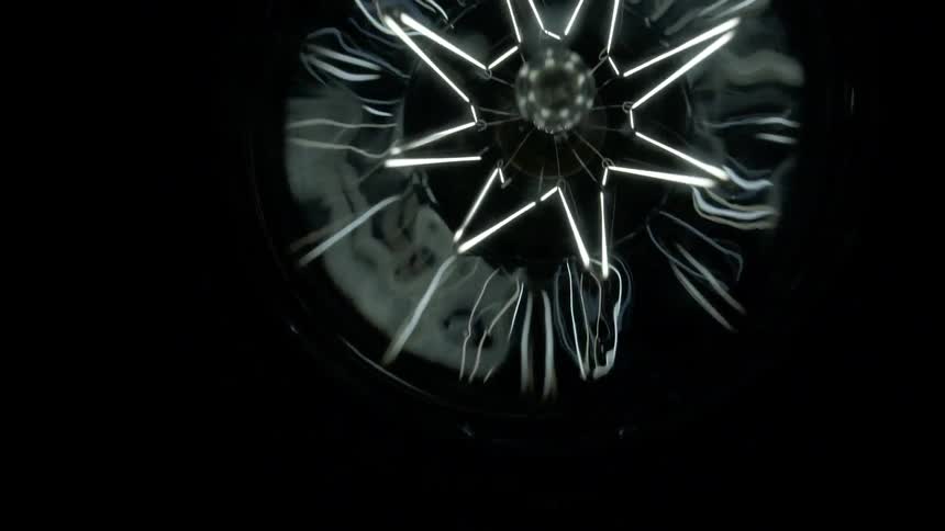 The filaments in a clear glass bulb glow and reflect against a black background