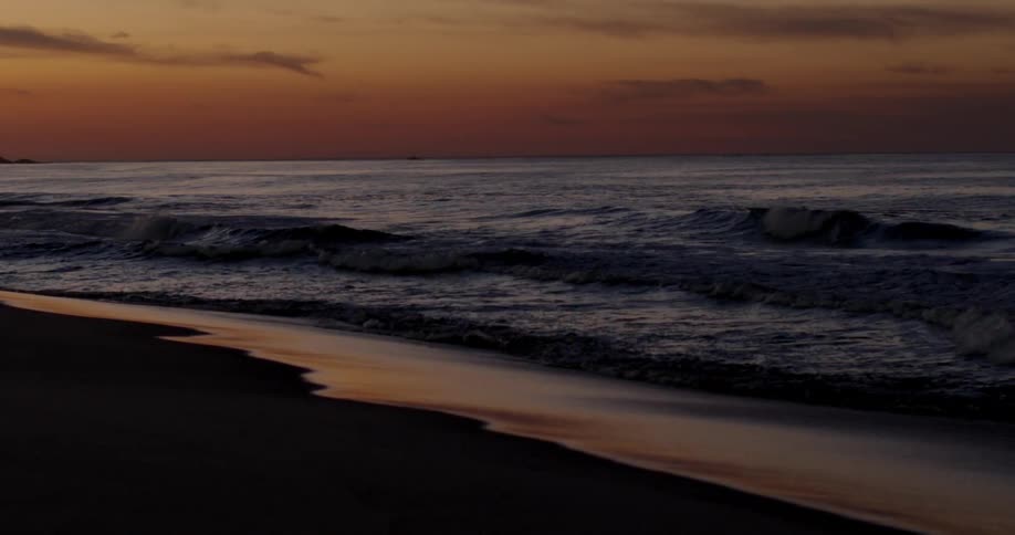 Waves are crashing along the beach coastline at sunrise