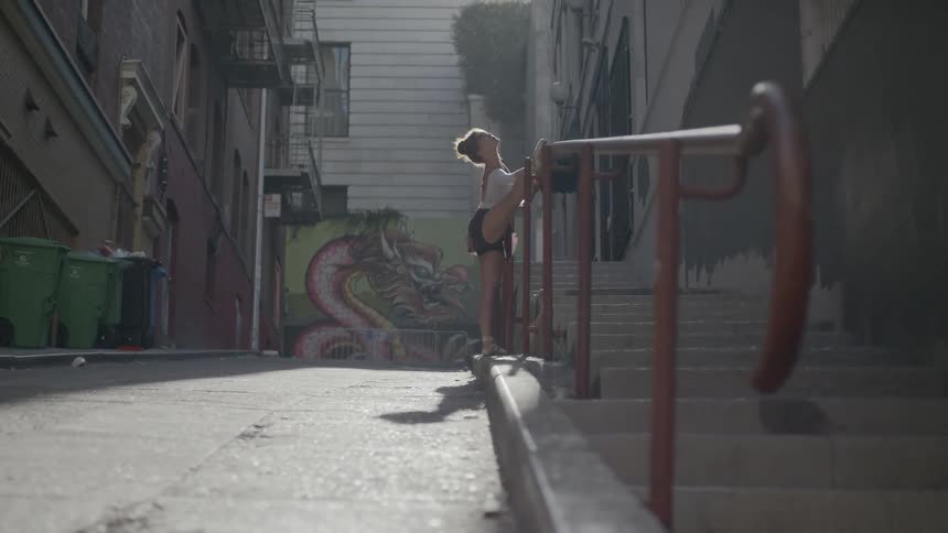 A woman is stretching in the alley