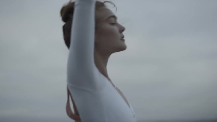A young female dancer gracefully holds her arms outward as she dances outside