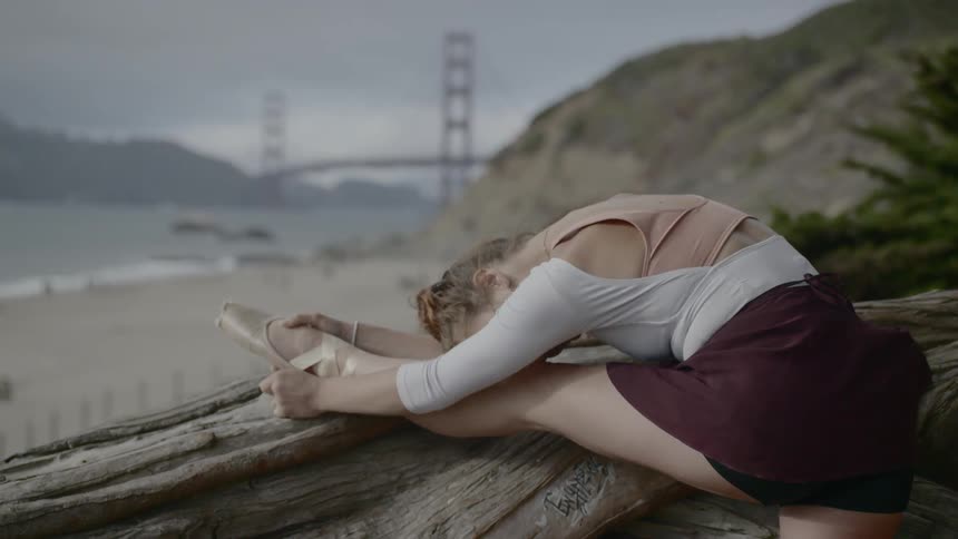 A ballet dancer stretching on a log