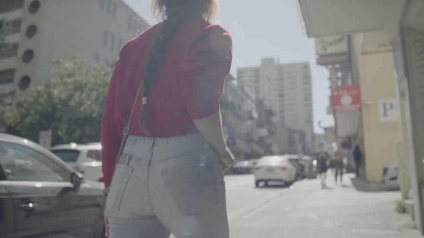 A woman walks down a city sidewalk