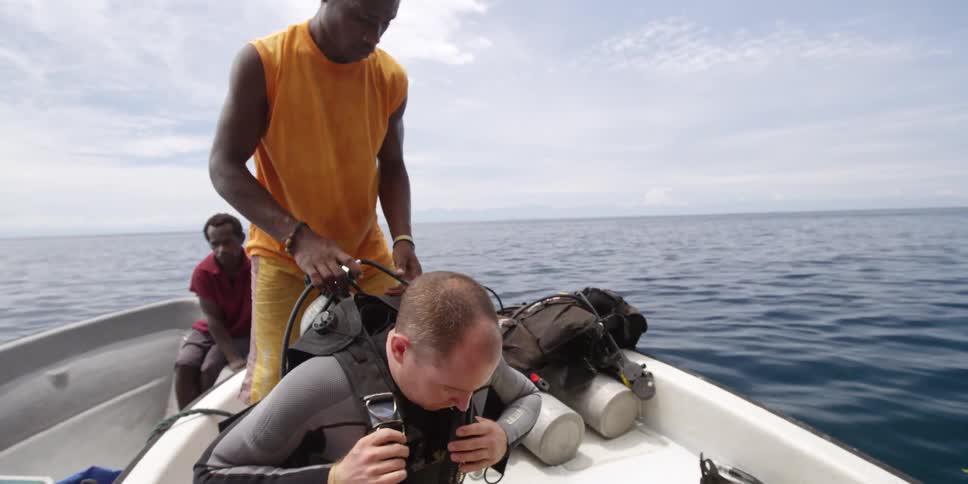 Scuba diver in a boat getting his gear on