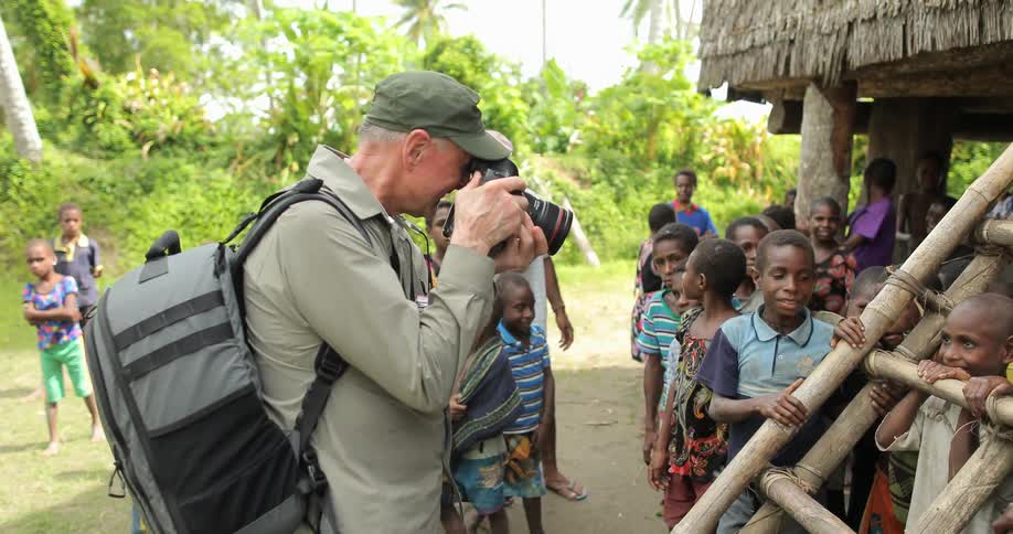 A man photographs children in a village