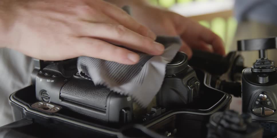 Man cleaning camera with a cloth