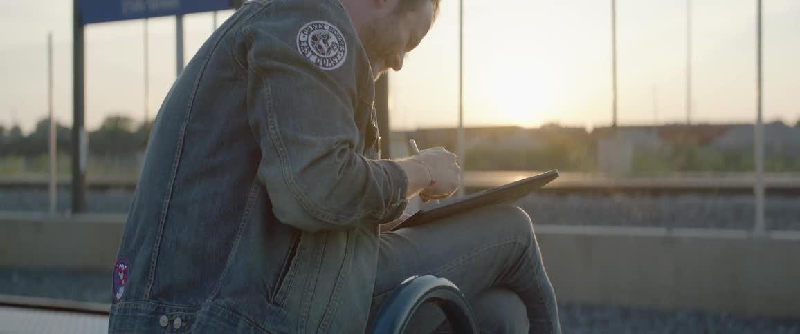 Man sits on bench writing in notebook