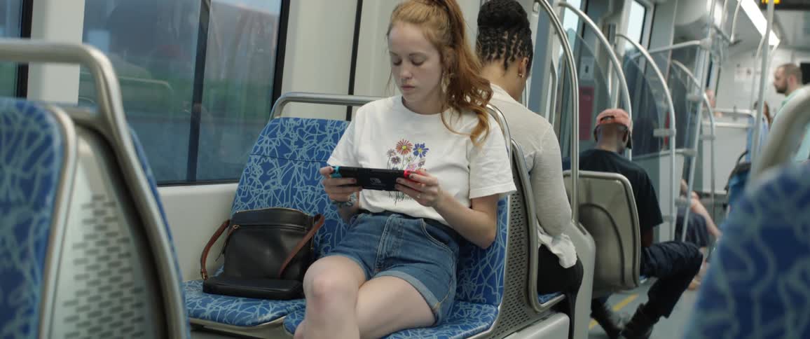 A young girl sits on a bus and looks at her electronic device
