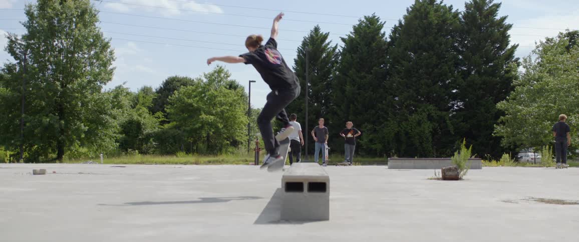 A boy rides his skateboard and jumps up on to a platform