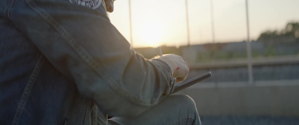 A man drawing on a tablet at dusk