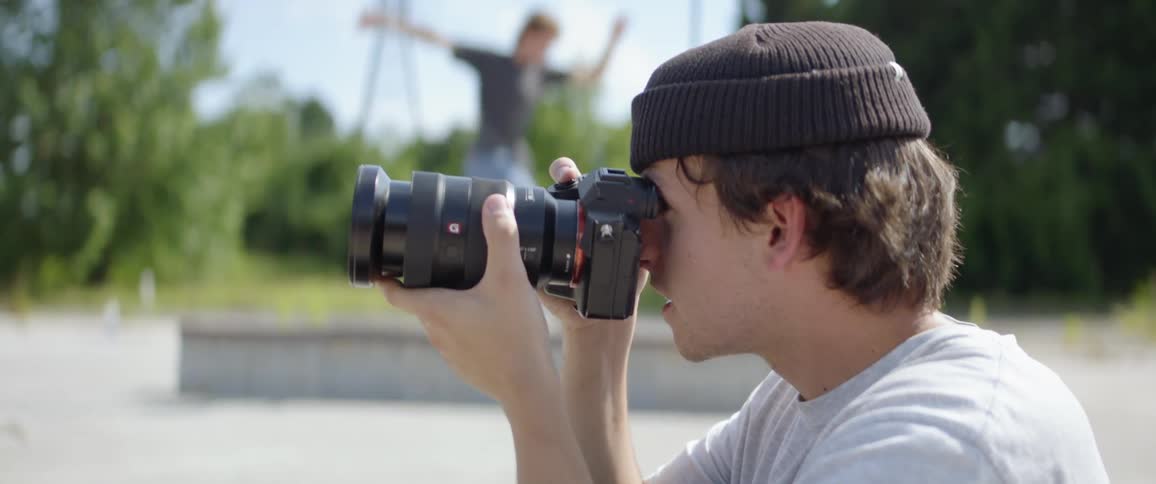 A man photographs people skateboarding in a park