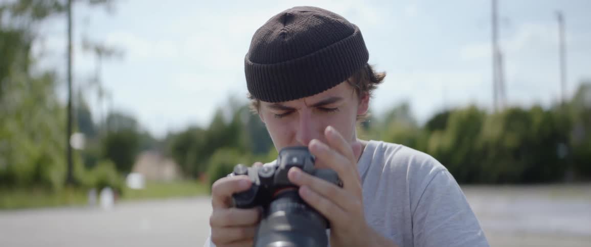 Photographer takes a shot then studies the picture outdoors