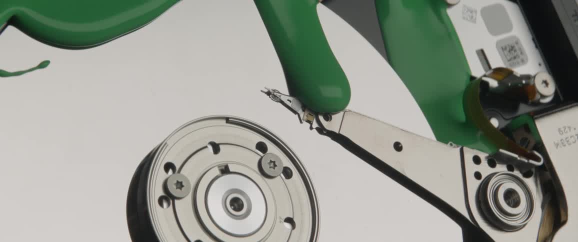 Green paint slowly oozes across the surface of the internal components of a computer hard disc drive