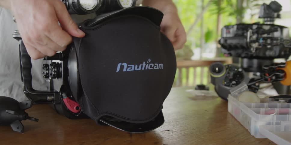 A person preparing underwater photographic gear on a table outside