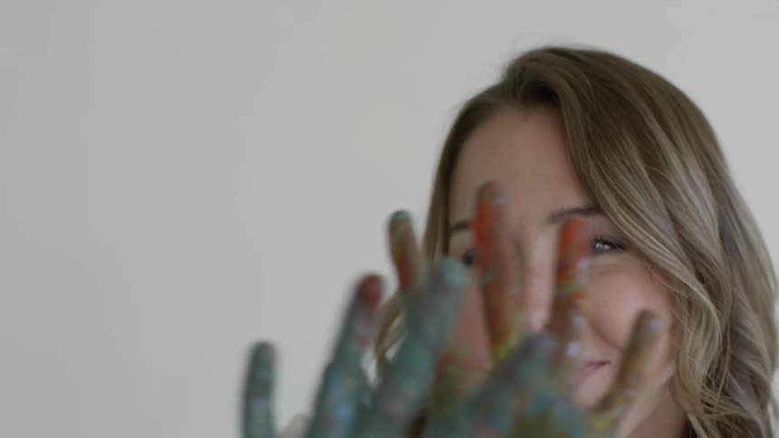 Woman with painted hands waving them in front of her face
