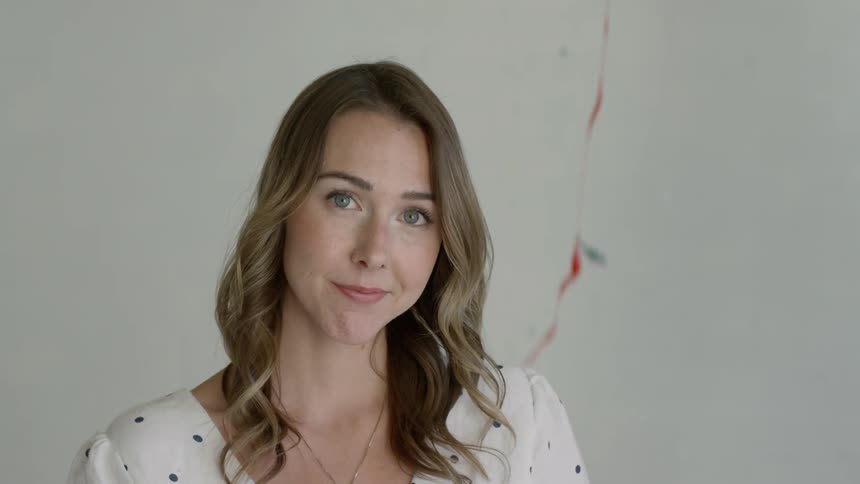A woman standing while paint is thrown in the background