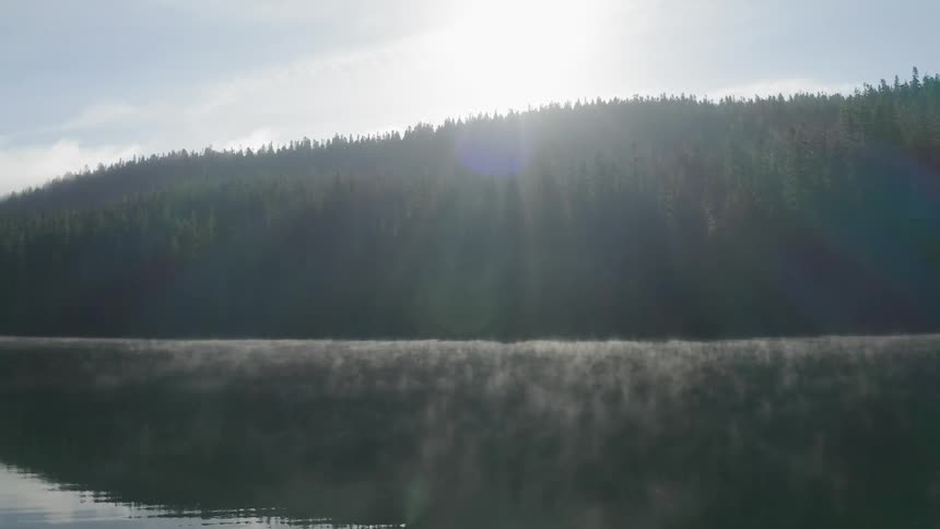 The sun rises over a lake surrounded by trees