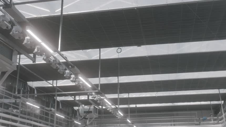 A scaffold with very bright lights hangs from the ceiling inside of a facility