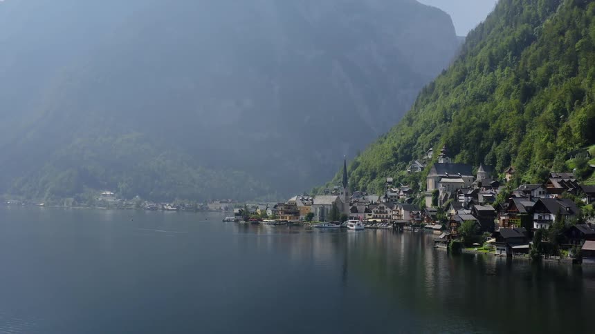 Boat cruises lake near town bordering mountains