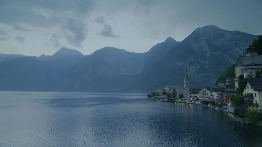 Mountains tower over wide lake and town on rainy day
