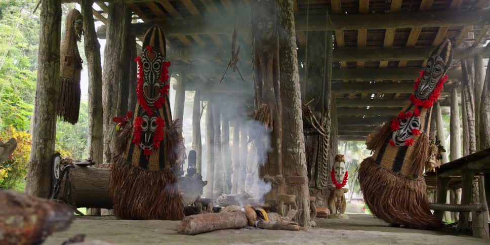 People in native costumes dance near a smoldering fire