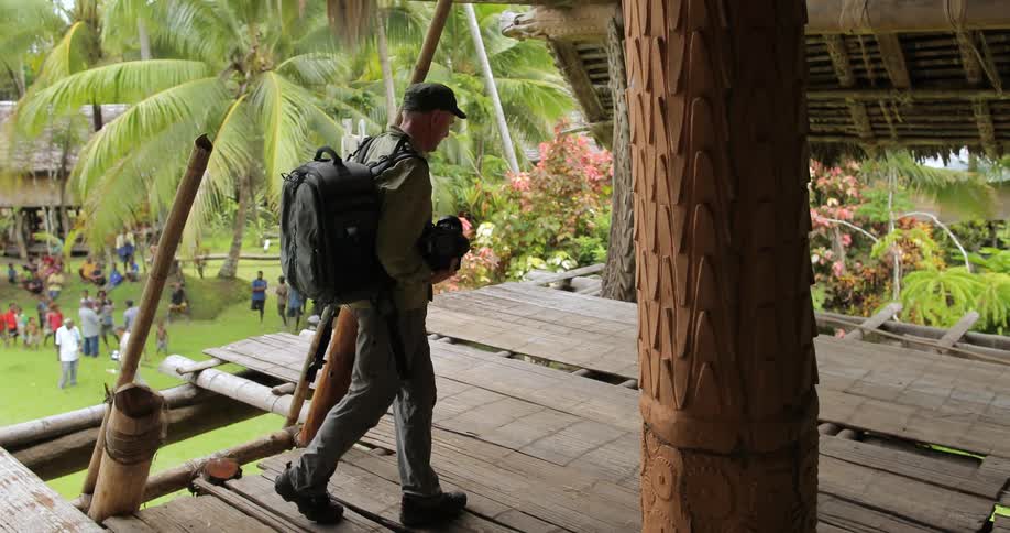 A man in a backpack climbing a onto a wooden deck